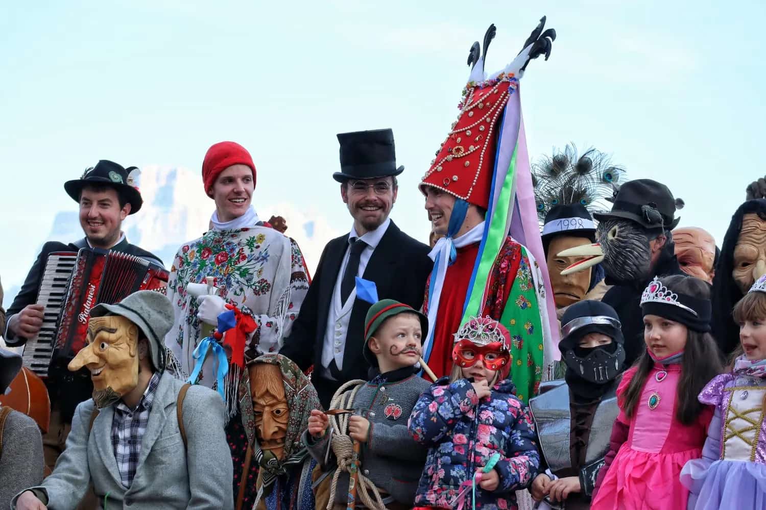 Costumed figures and hand-carved wooden masks gathered for the Ladin Carnival in the Dolomites