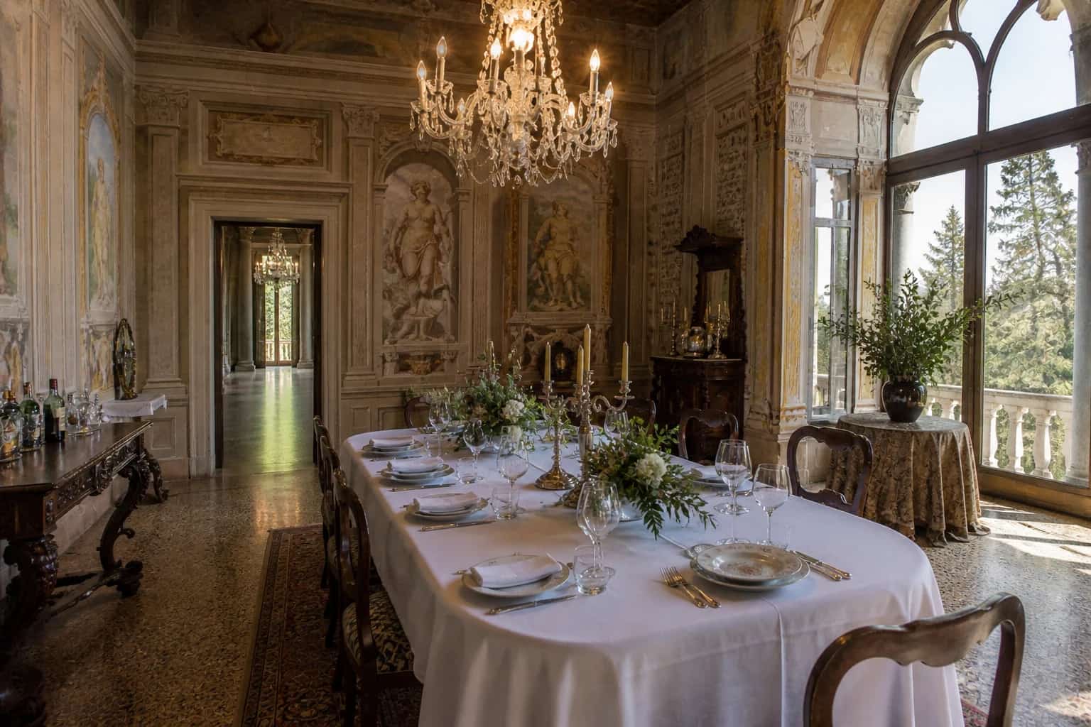 A candlelit table laid in the frescoed salon of a historic Dolomite villa