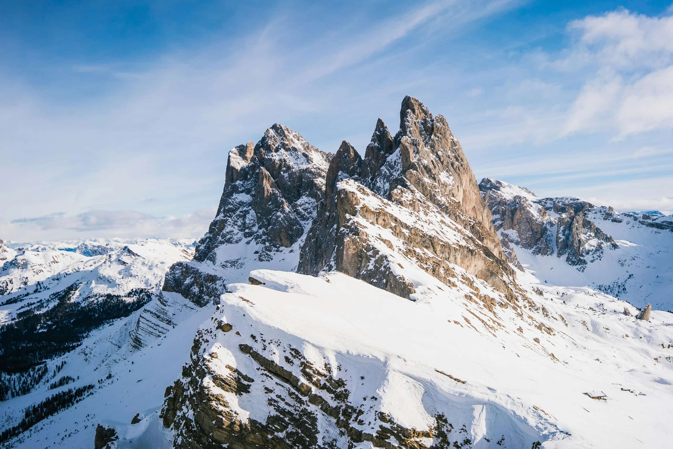 Snow-covered jagged ridgelines of the Dolomites under a bright winter sky